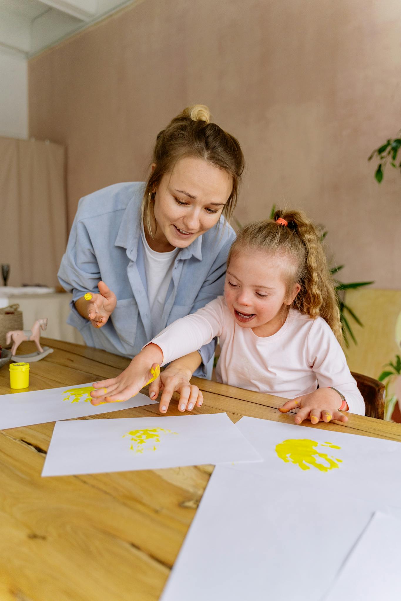 A mother and daughter joyfully painting handprints at home, fostering creativity and bonding.
